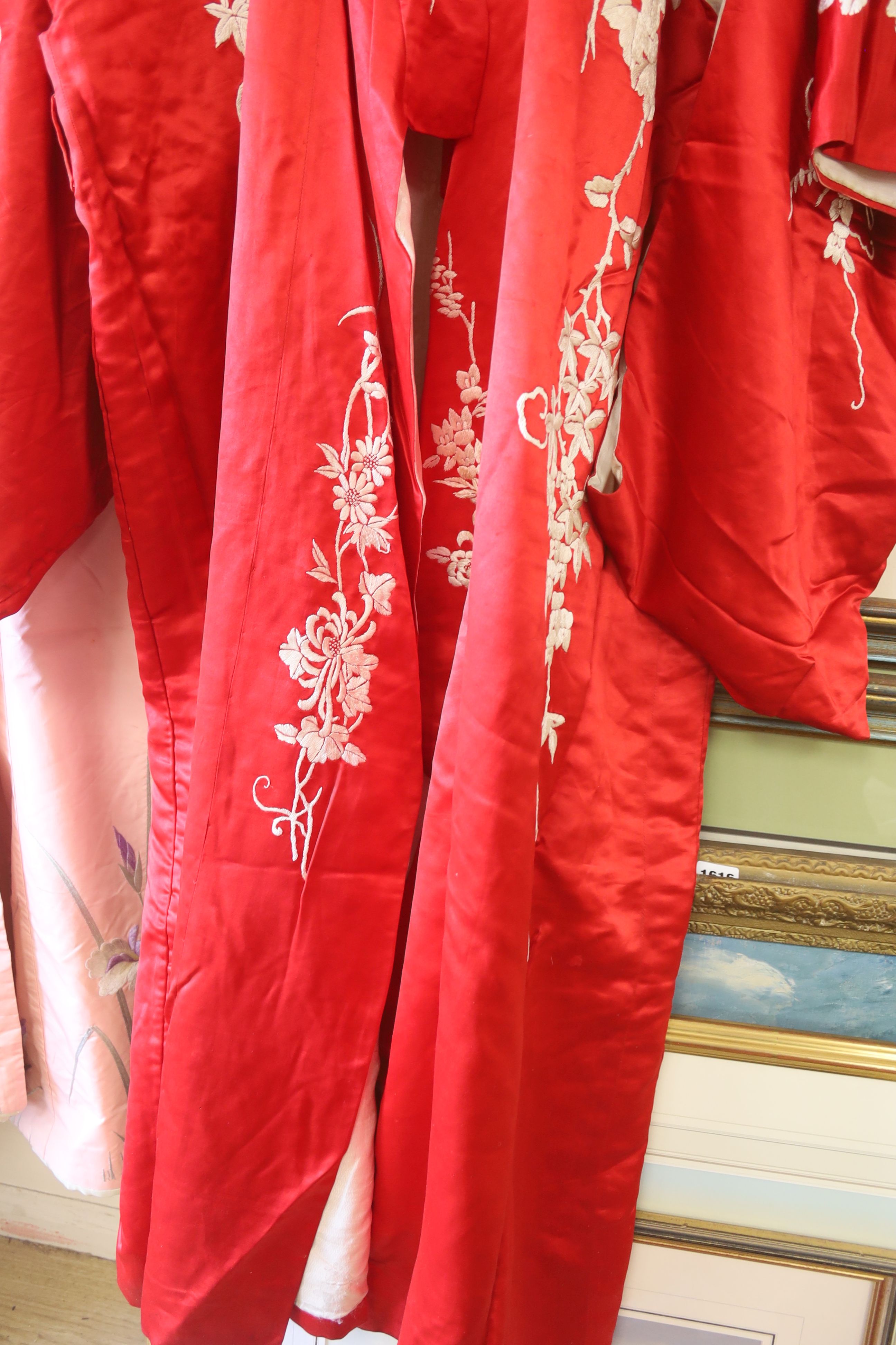 A pink silk Japanese kimono embroidered with wisteria and irises and butterflies, length 140cm, together with a red kimono embroidered with white wisteria and carnations